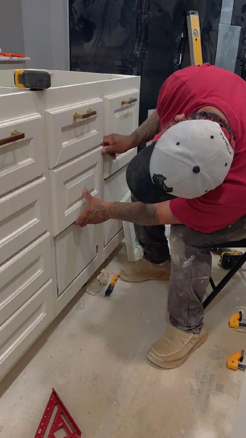 Worker installing a white bathroom vanity cabinet